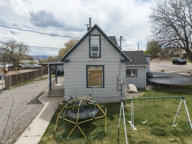 Back of property with a trampoline, an outdoor fire pit, and a shingled roof