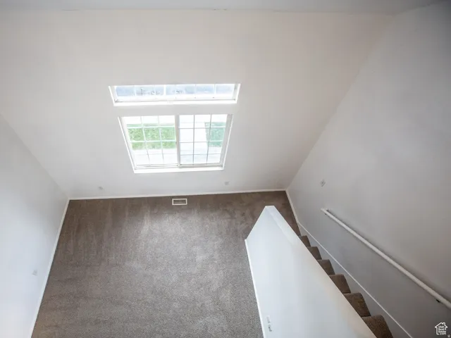 Unfurnished room featuring carpet flooring, a skylight, and lofted ceiling