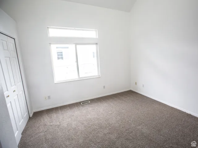 Unfurnished bedroom featuring dark colored carpet and a closet