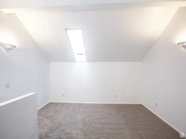 Additional living space with carpet floors and vaulted ceiling