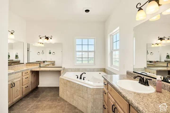 Corner jetted tub set within a tiled surround, complemented by dual vanity areas featuring wood cabinetry and speckled countertops