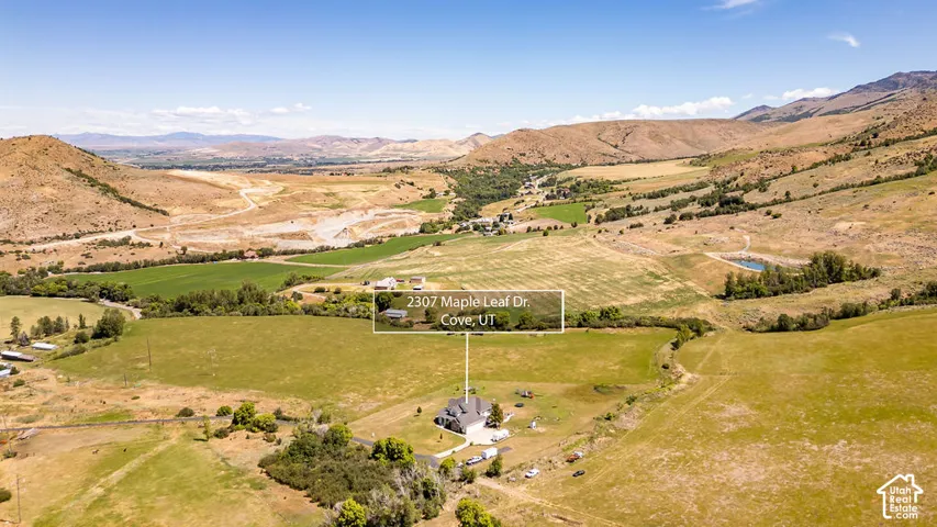 Expansive property featuring a single-family residence with an attached garage, set amidst vast open fields and distant mountainous terrain
