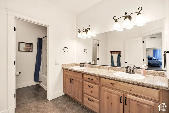 Double vanity with light wood cabinetry, speckled countertop, and integrated sinks