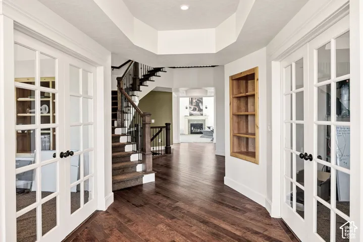 Foyer with rich wood-finish flooring, white trim, and a built-in wooden shelving unit