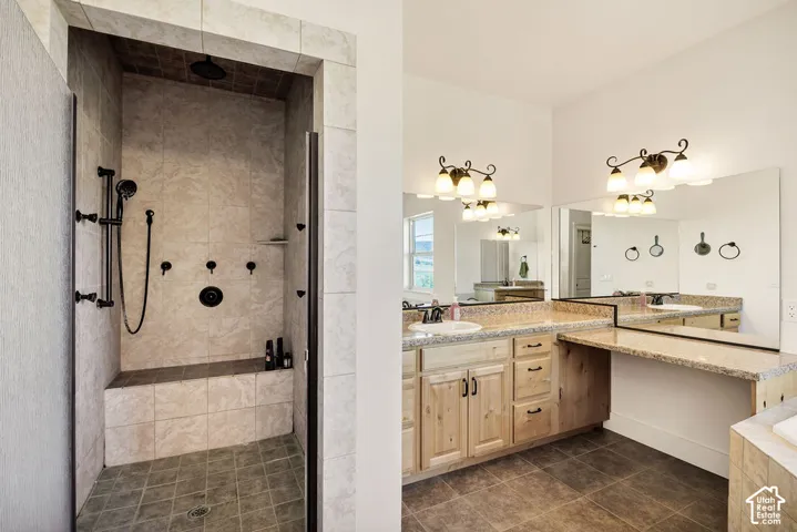 Spacious bathroom featuring a large walk-in shower with a built-in bench and multiple shower heads, dual vanity sinks, extensive counter space, and integrated lighting fixtures