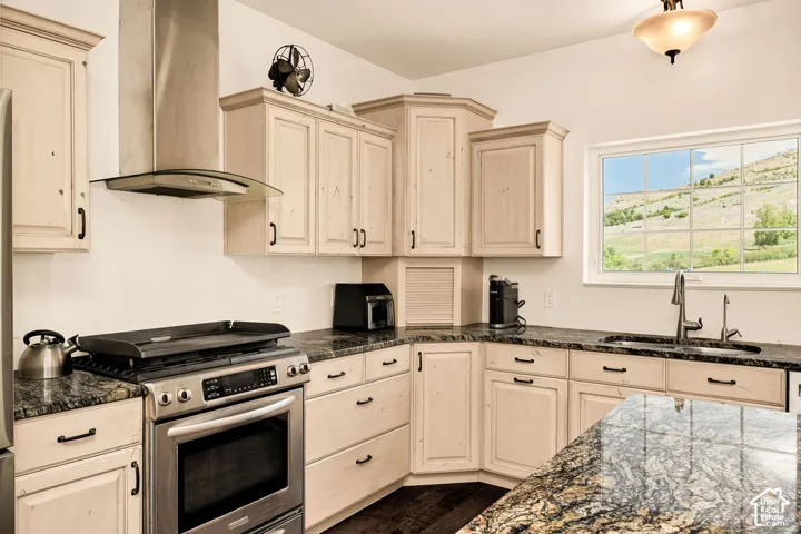 Kitchen featuring light-toned cabinetry with dark hardware, granite countertops, a stainless steel range with overhead hood, and a window presenting a mountain landscape