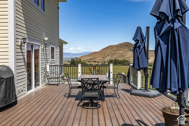Spacious outdoor deck featuring wood-finish flooring, white railings with black balusters, and a sliding glass door