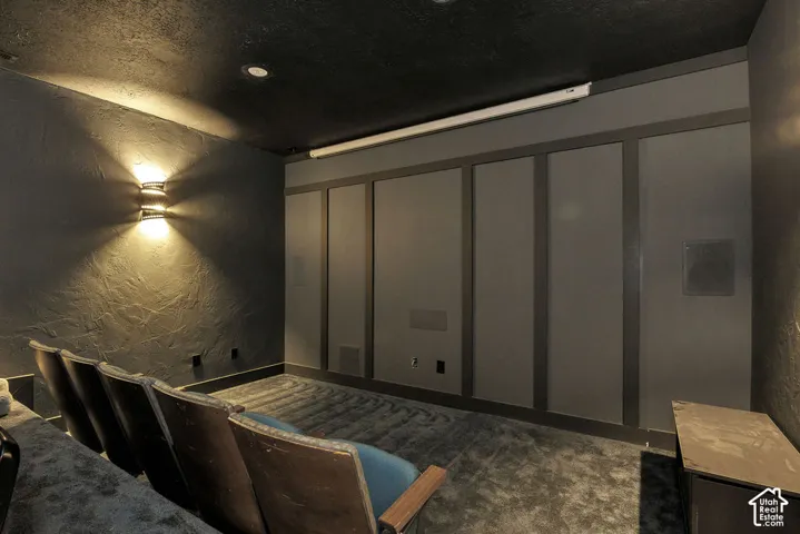 Dedicated media room featuring built-in audio components, dark textured walls, and a low-profile ceiling