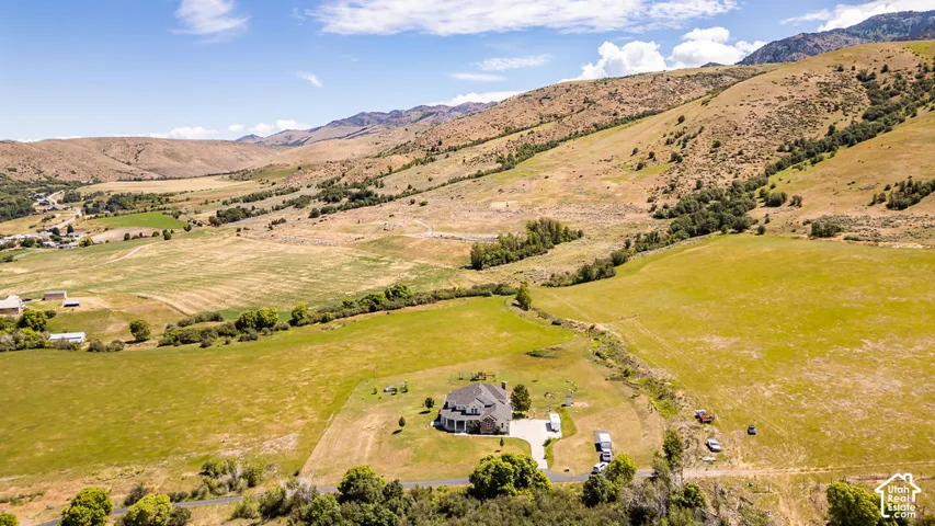 Expansive property featuring a large residence with a circular drive, surrounded by sprawling green fields and distant mountains