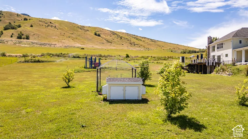 Expansive property featuring a two-story residence with a multi-level deck, a detached storage shed, and mature trees
