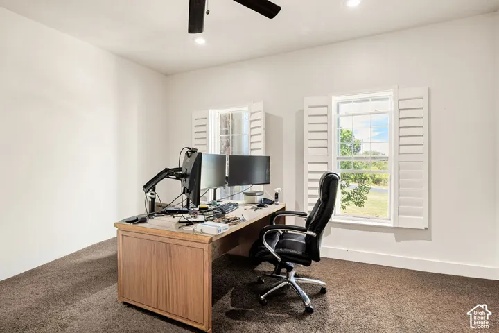Room featuring two windows with white plantation shutters, neutral wall tones, and dark carpet