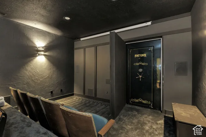 Dedicated media room with textured walls, built-in wall speakers, and a secure vault door