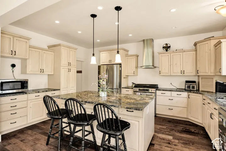 Kitchen featuring wood-finish flooring, a central island with a stone countertop, light-toned cabinetry, stainless steel appliances, and recessed lighting