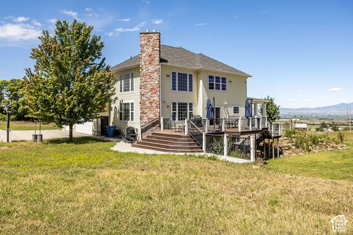Two-story residence featuring light-colored siding and a substantial stone chimney