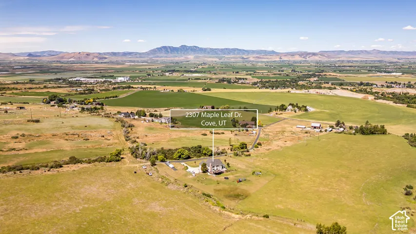Expansive aerial view showcasing a residence amidst vast open fields and distant mountains