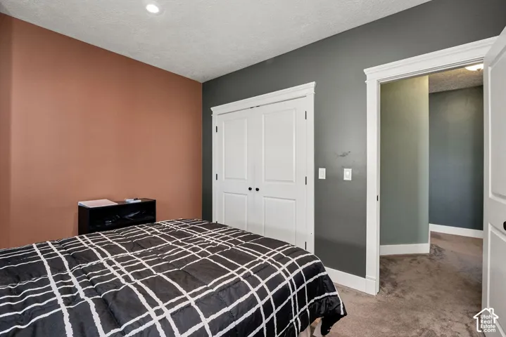Bedroom featuring a single recessed ceiling light, textured carpet flooring, and two-tone wall finishes