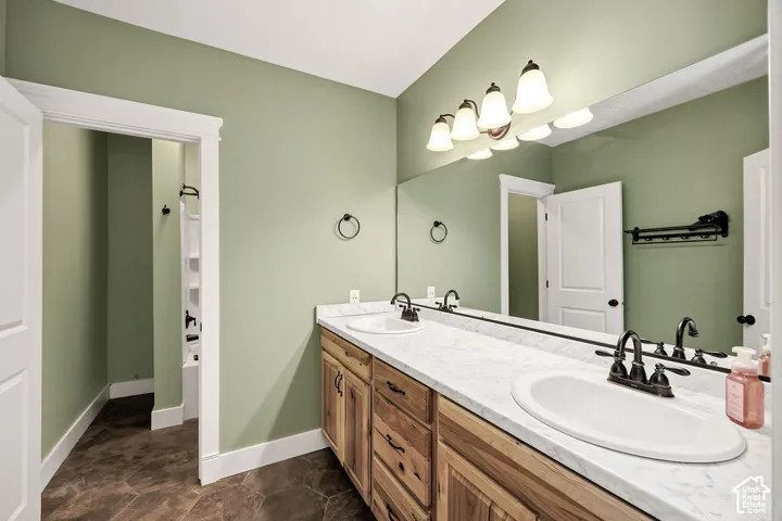 Double vanity featuring wood-finish cabinetry, white countertops, and dual oval sinks with dark bronze fixtures