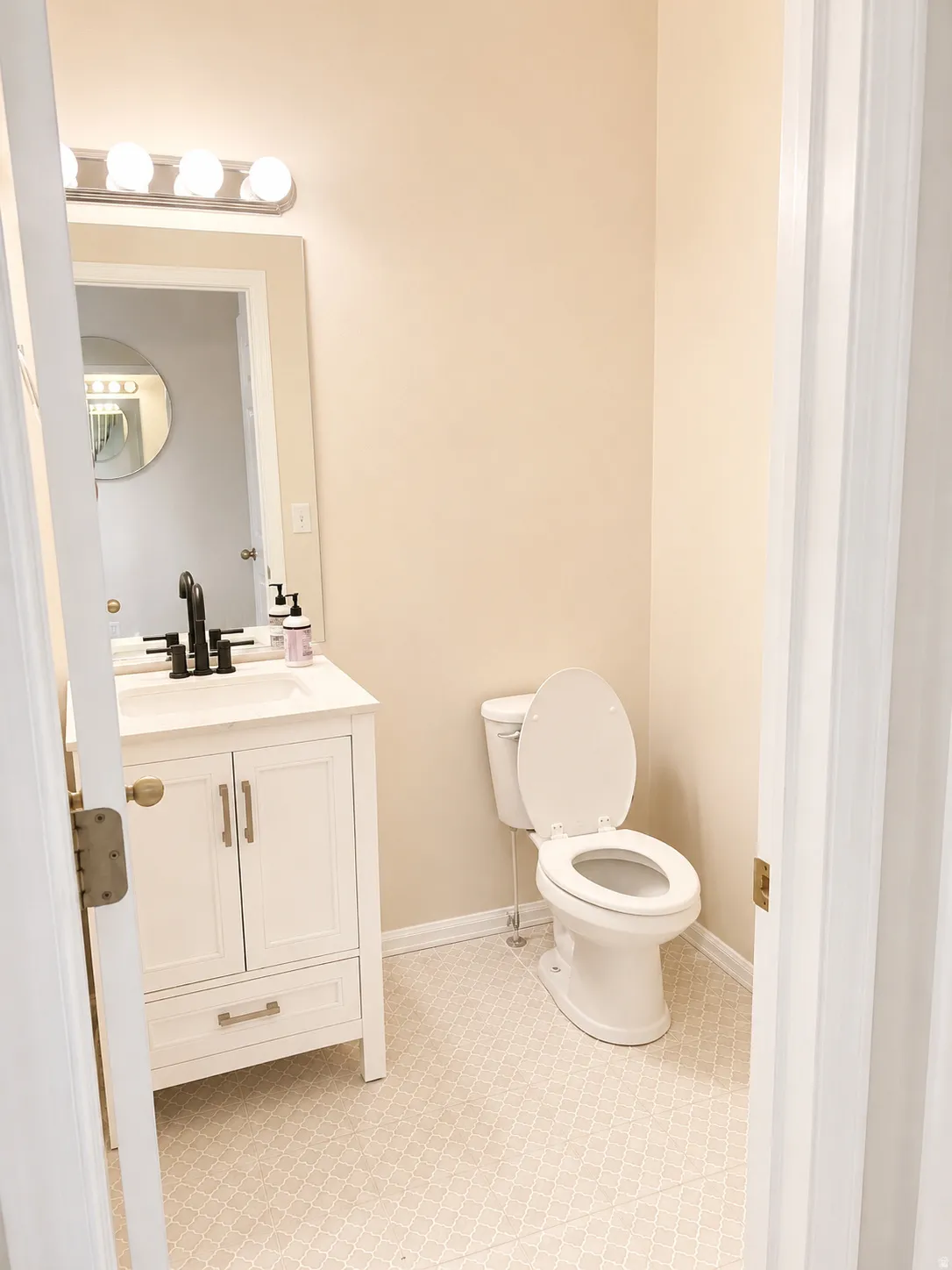 Bathroom featuring a white vanity with brushed nickel hardware, a white sink, and a black faucet