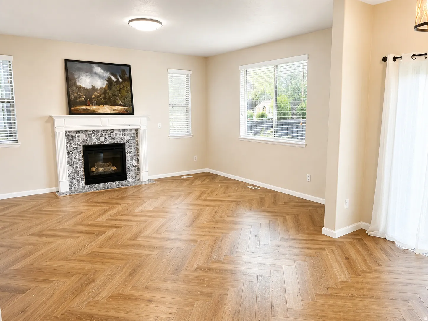 Herringbone wood-finish flooring complements a gas fireplace with a tiled surround and white mantel