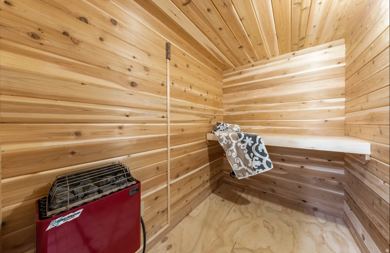 Sauna featuring wood walls, wood ceiling, and marble finish floors