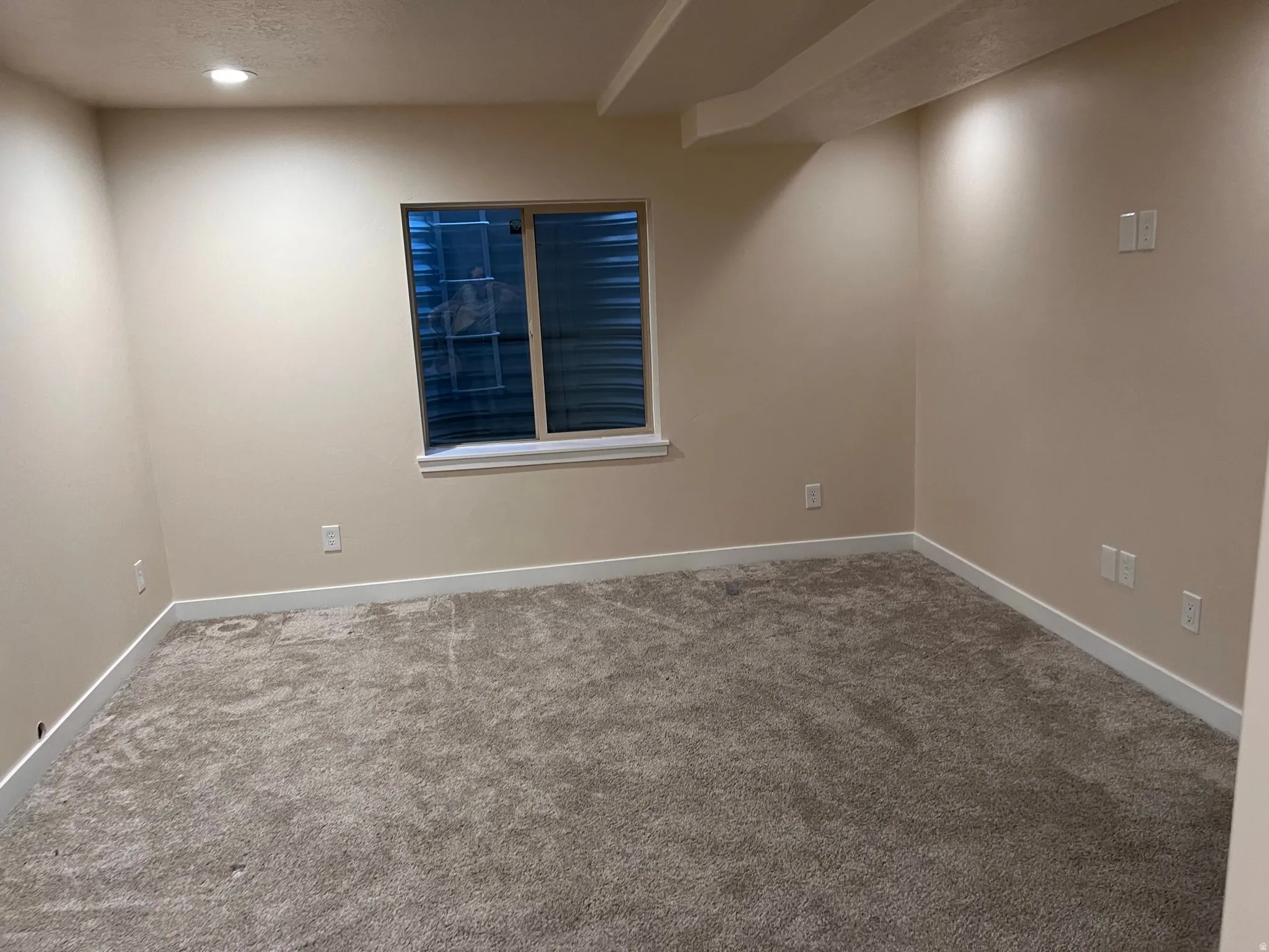 Carpeted spare room with a textured ceiling and baseboards