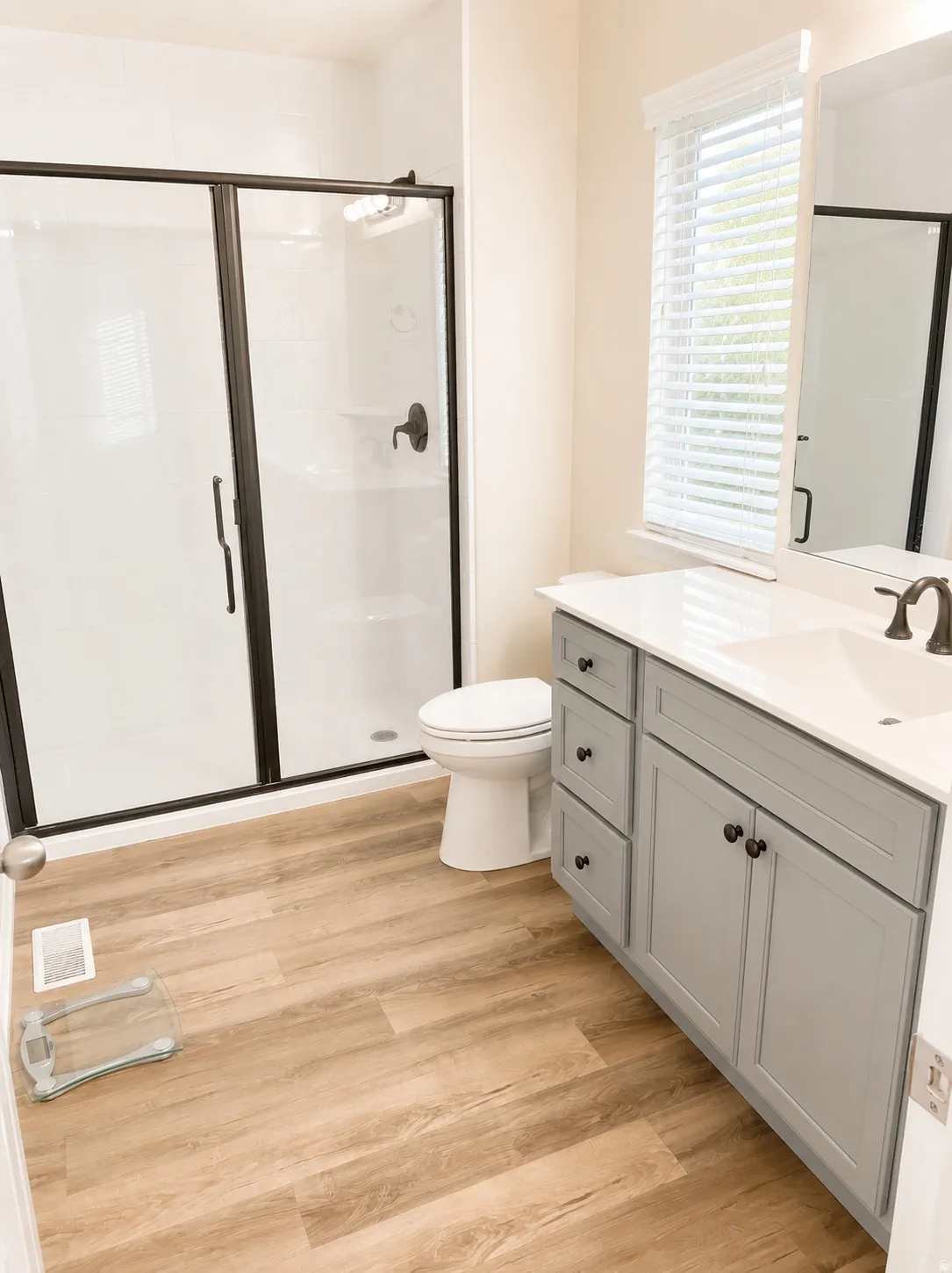 Bathroom featuring a dual vanity with grey cabinetry, white countertops, and dark bronze fixtures