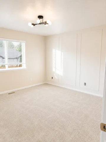 Light-colored carpeting and a contemporary black and brass ceiling fixture highlight this room