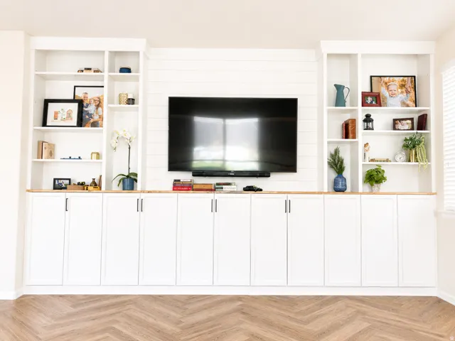 Built-in media center featuring white cabinetry, wood-finish countertops, and shelving units