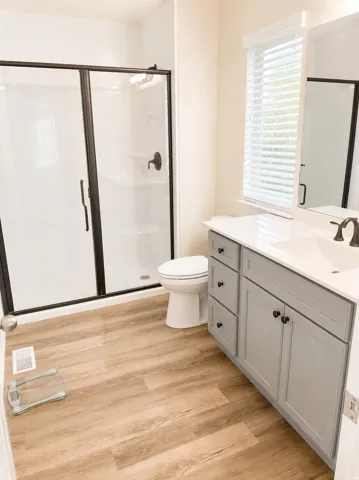Bathroom featuring a dual vanity with grey cabinetry, white countertops, and dark bronze fixtures