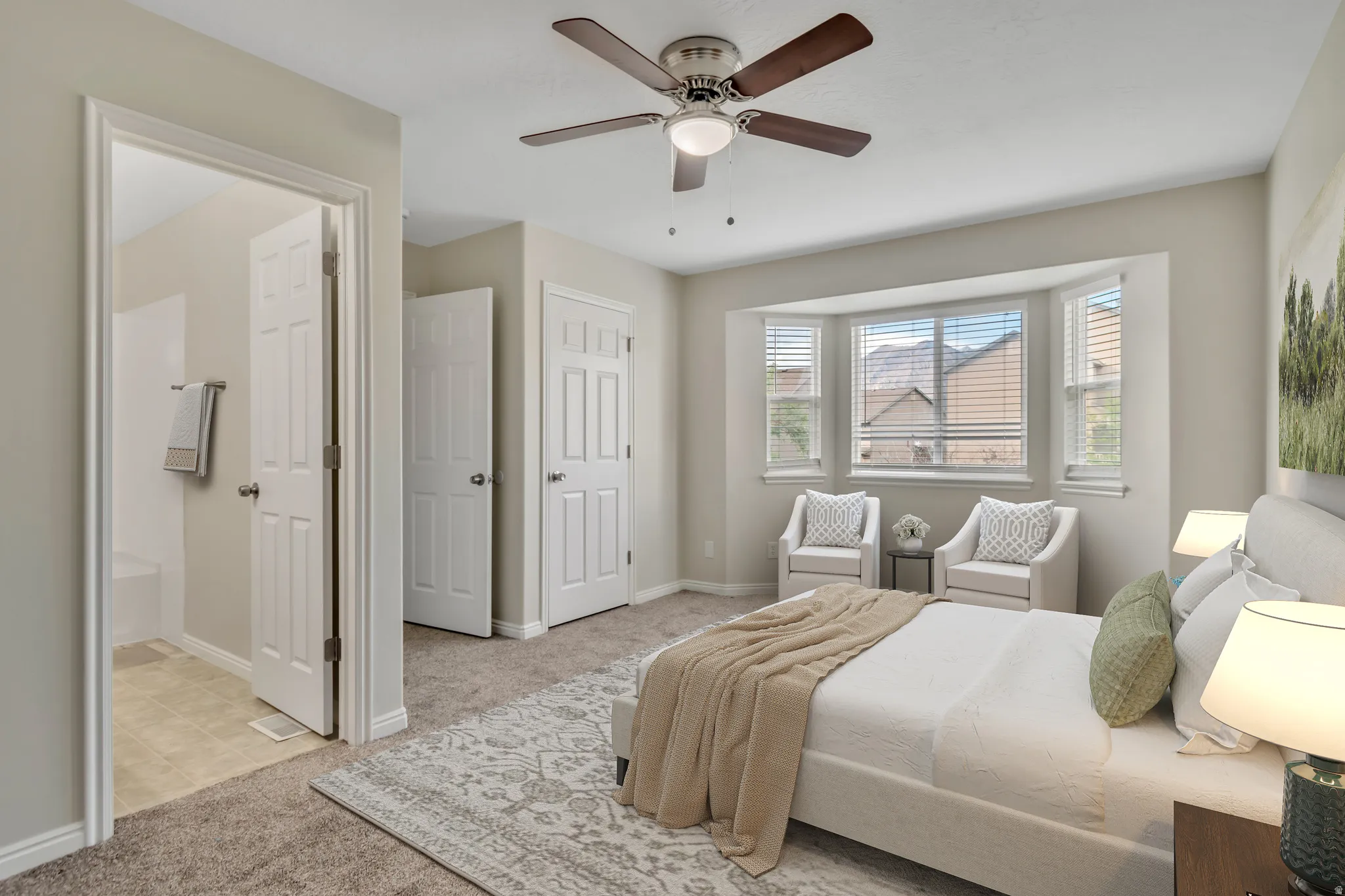 Bedroom featuring light carpet, ceiling fan, and ensuite bathroom