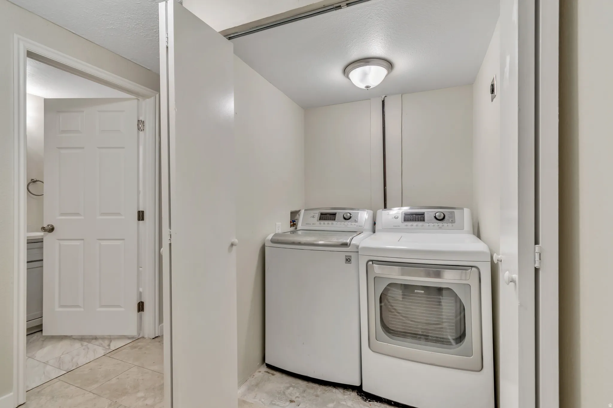 Laundry area with washing machine and dryer and a textured ceiling