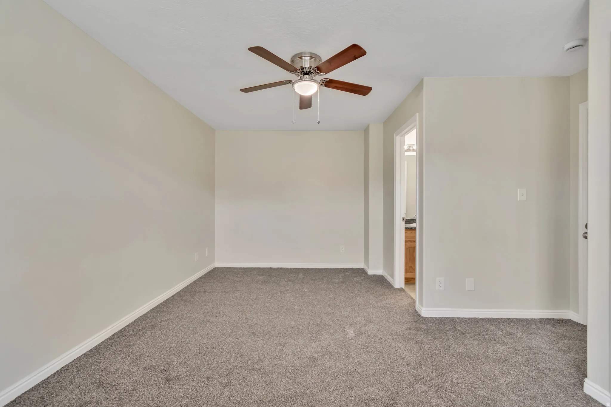 Carpeted empty room featuring baseboards and a ceiling fan