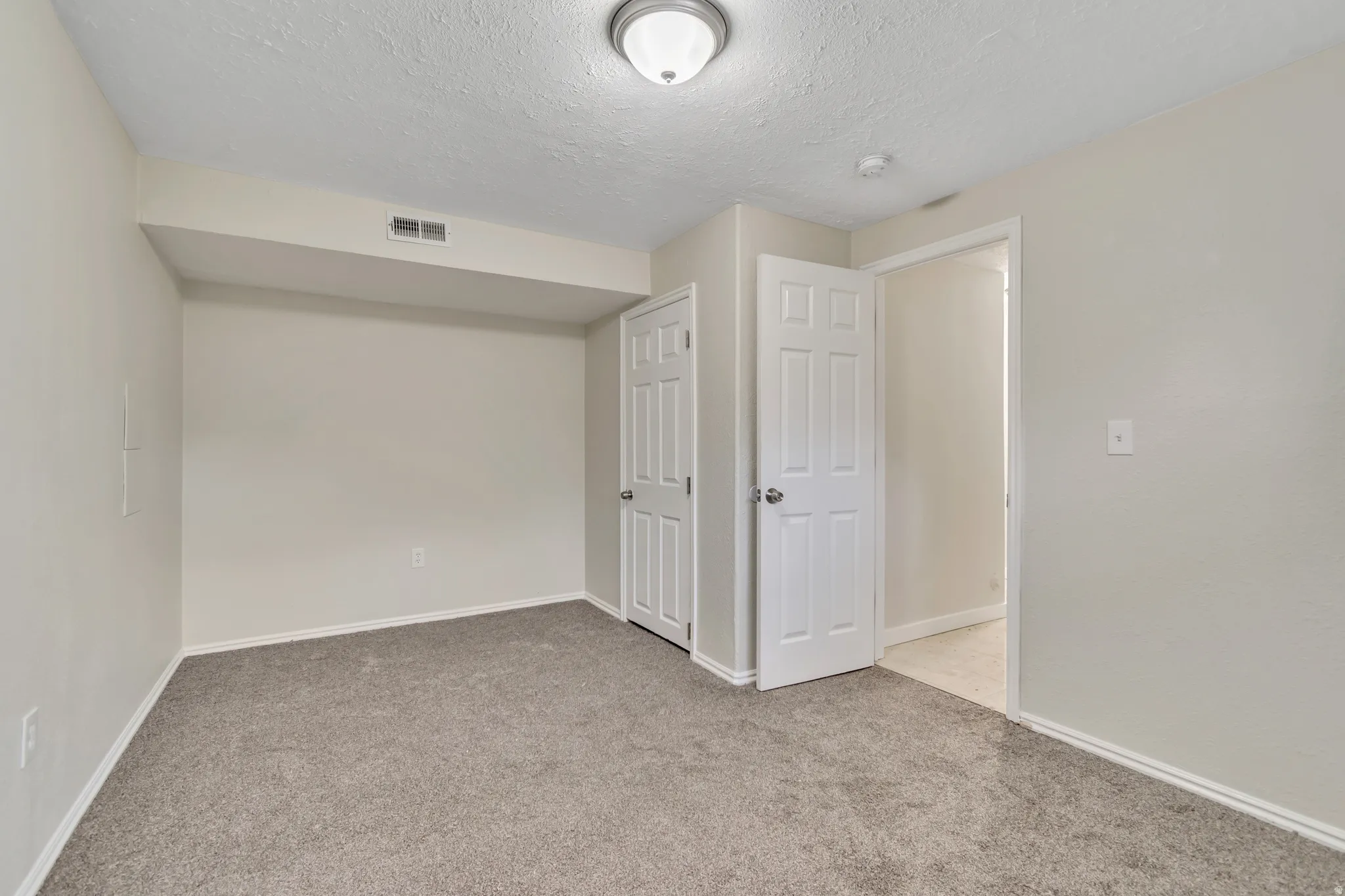 Unfurnished bedroom with light carpet, a textured ceiling, and a closet