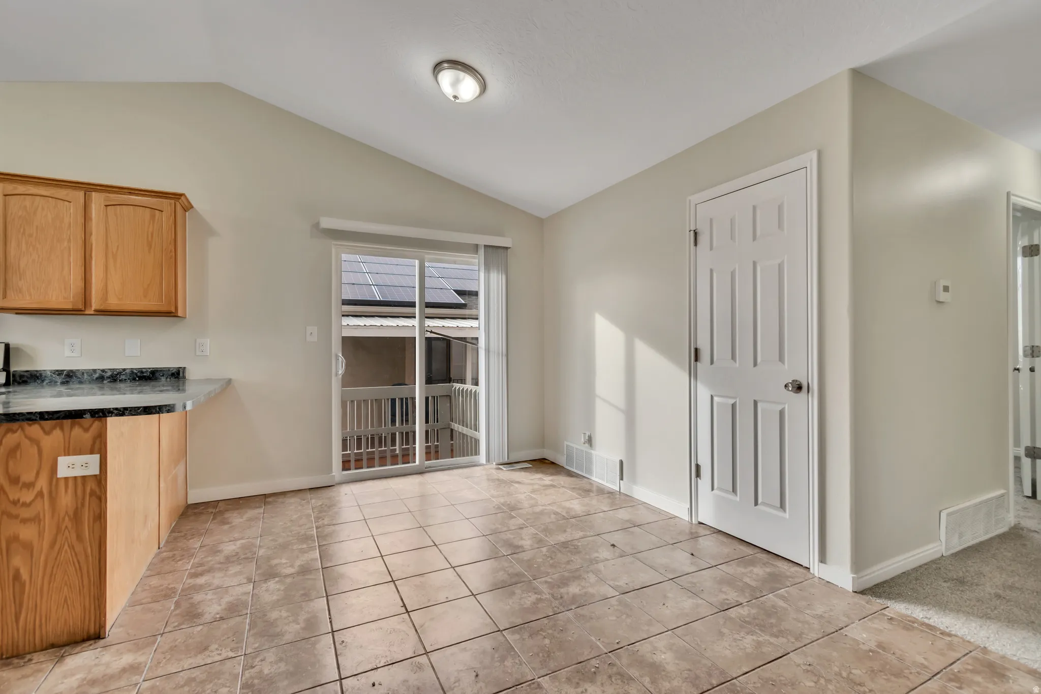 Unfurnished dining area with lofted ceiling and light tile patterned floors