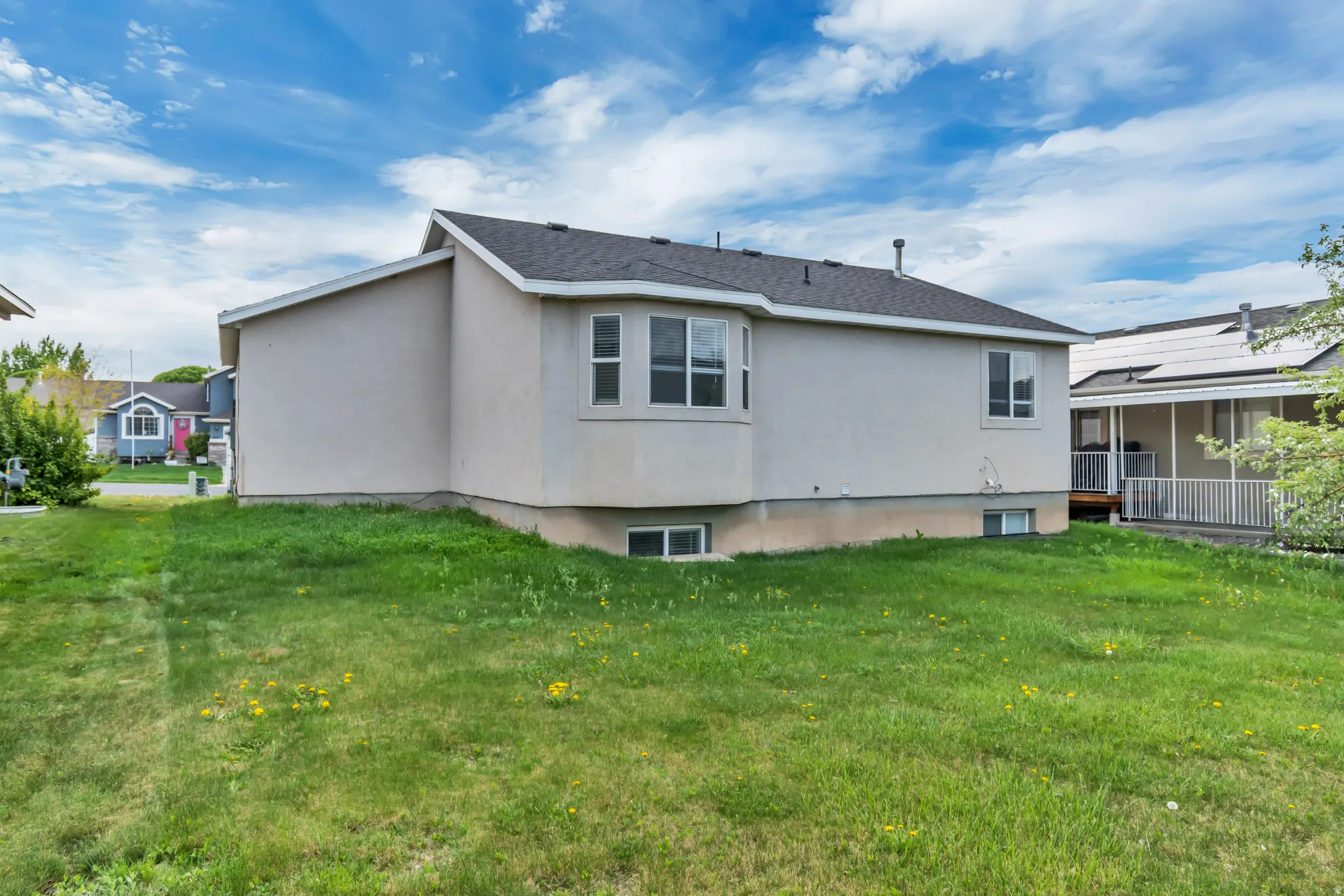 Rear view of house with a lawn, stucco siding, and a sunroom