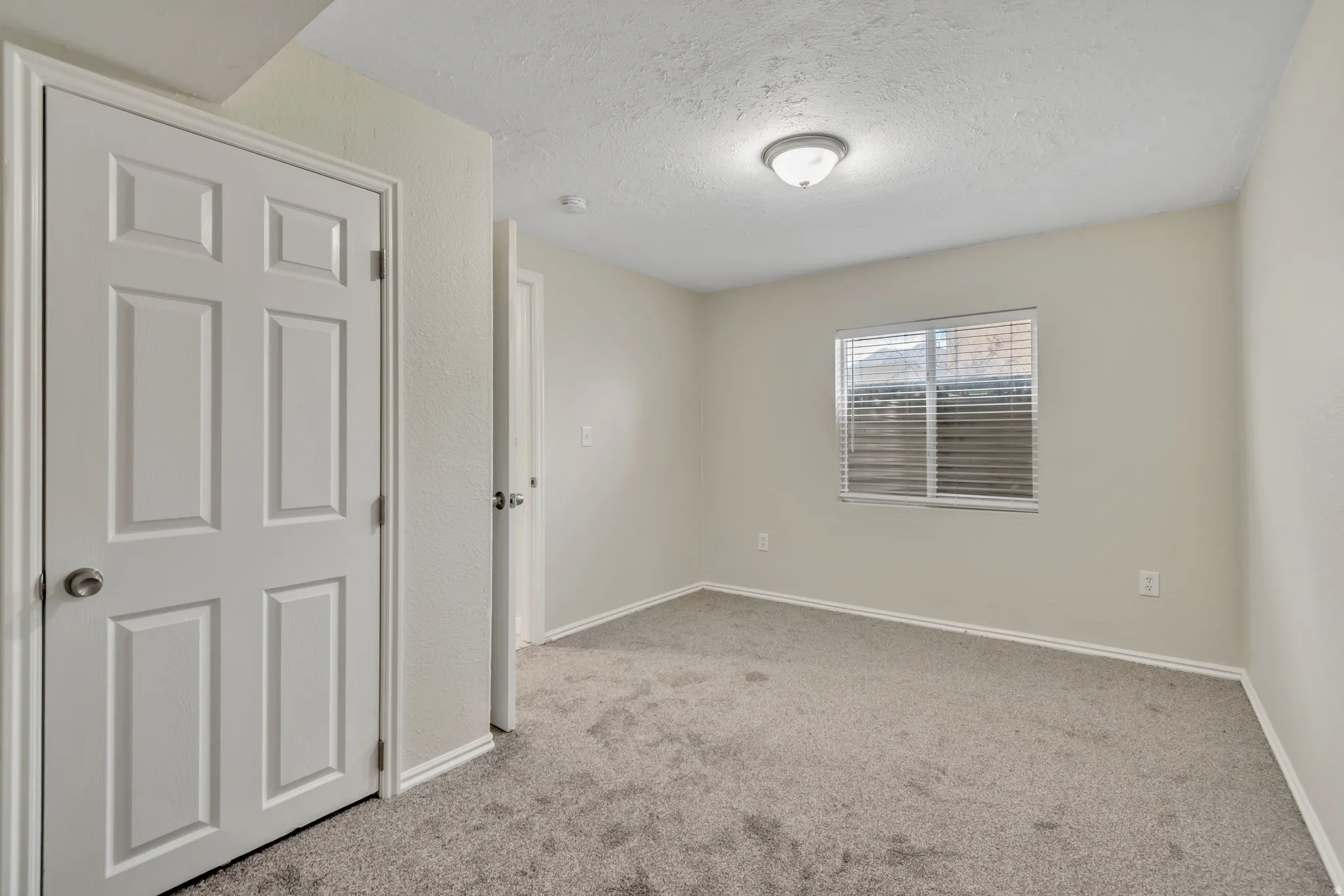Empty room with a textured ceiling and light carpet