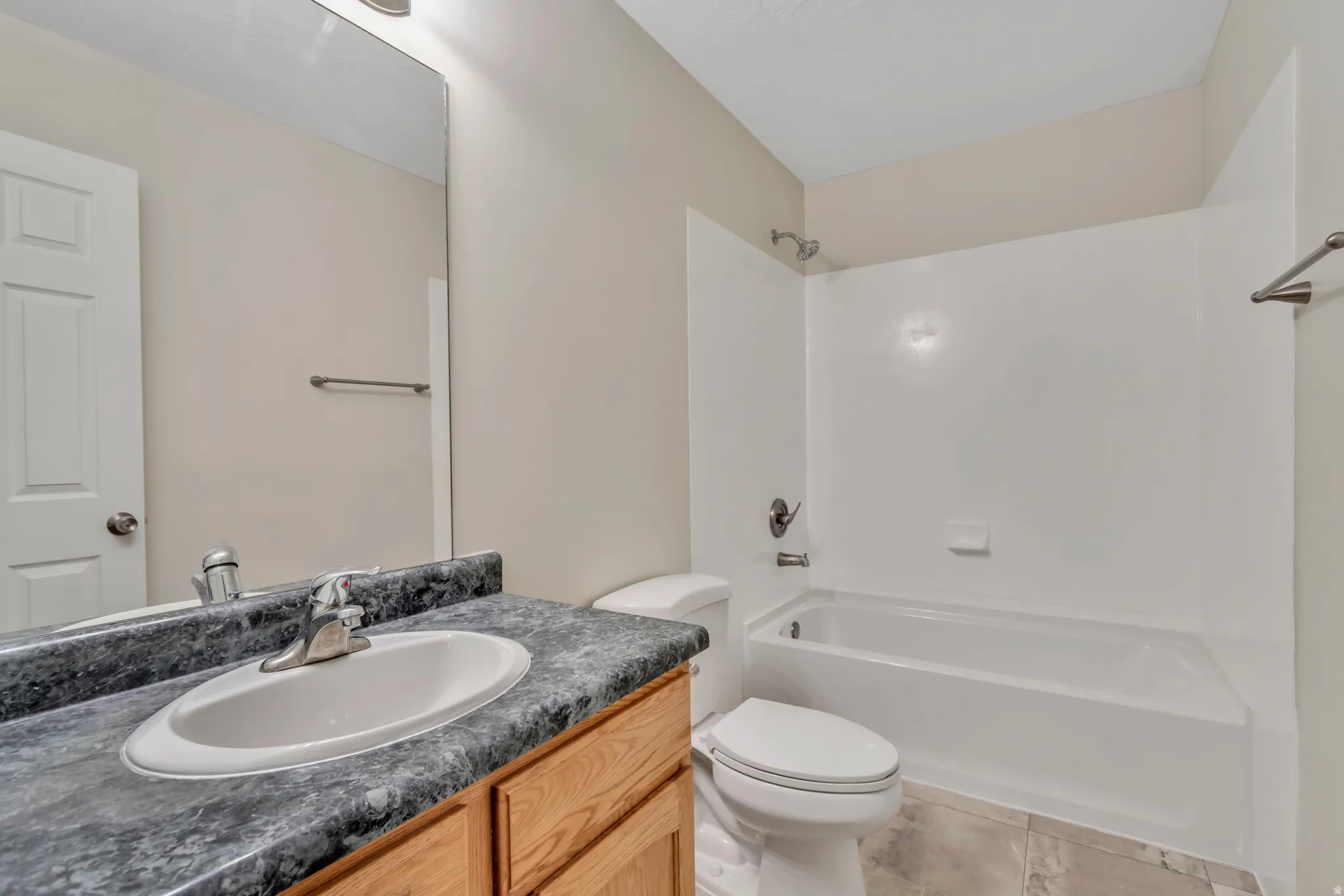 Bathroom with vanity, bathing tub / shower combination, and light tile patterned flooring
