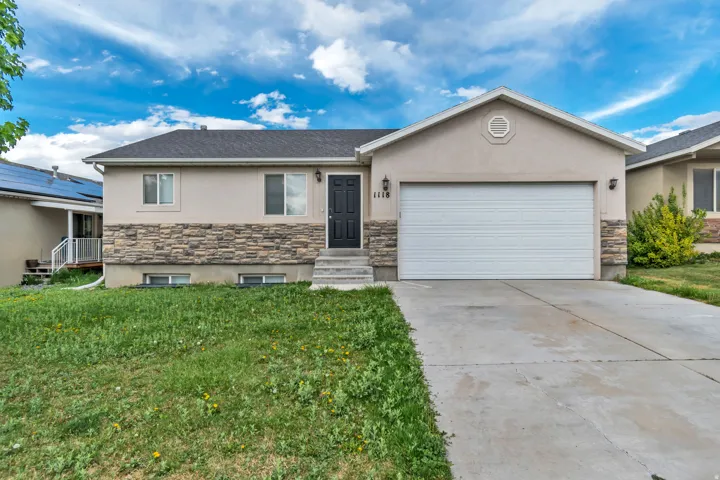 Ranch-style home with stone siding, stucco siding, an attached garage, and concrete driveway
