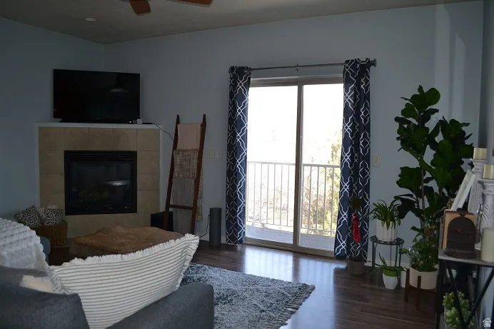 Living room featuring a tile fireplace, wood finished floors, and ceiling fan