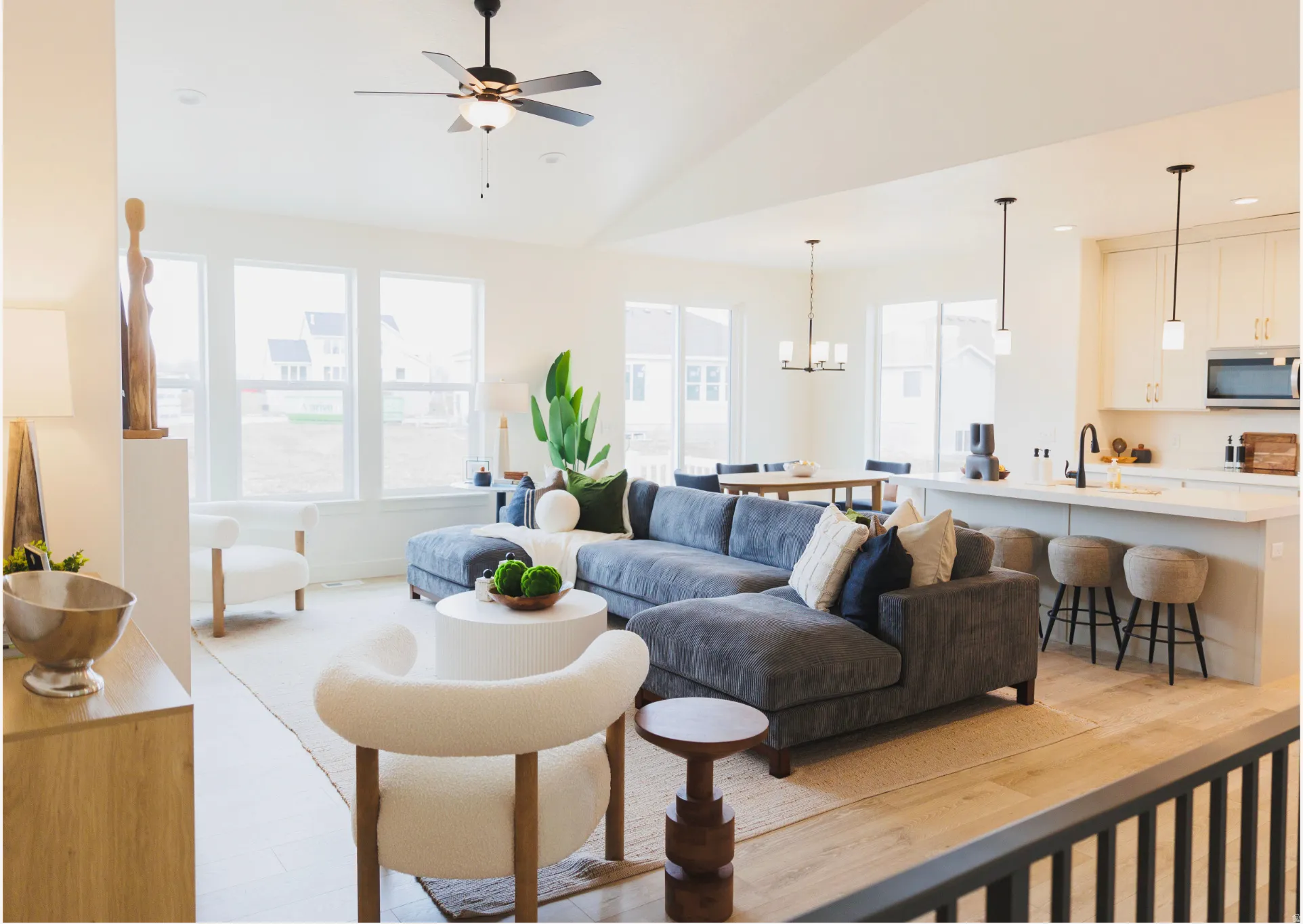 Open-concept living area with wood-finish flooring, vaulted ceilings, and large windows