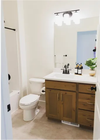 Bathroom featuring a wood-finish vanity with a white countertop, an undermount sink, and a black faucet