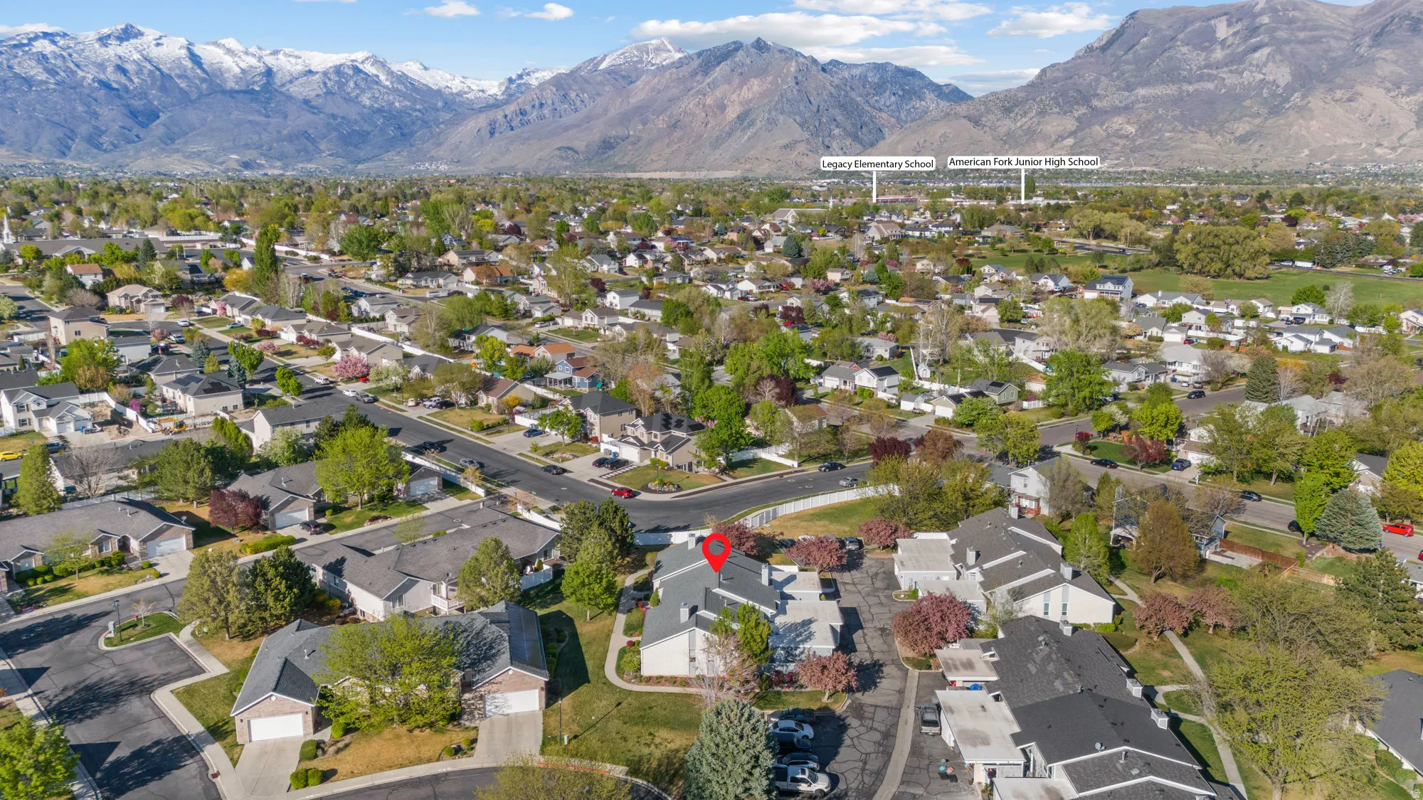 Aerial view of property and surrounding area featuring a mountainous background and nearby suburban area