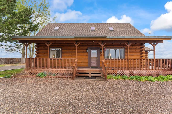 Back of property featuring log siding, covered porch, and a shingled roof