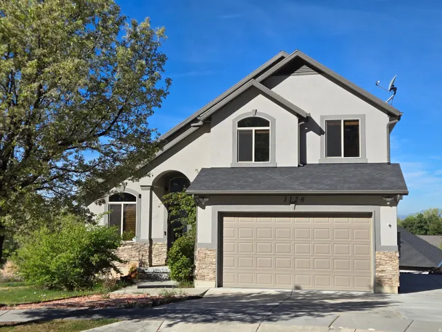 View of front facade featuring stone siding, stucco siding, and driveway
