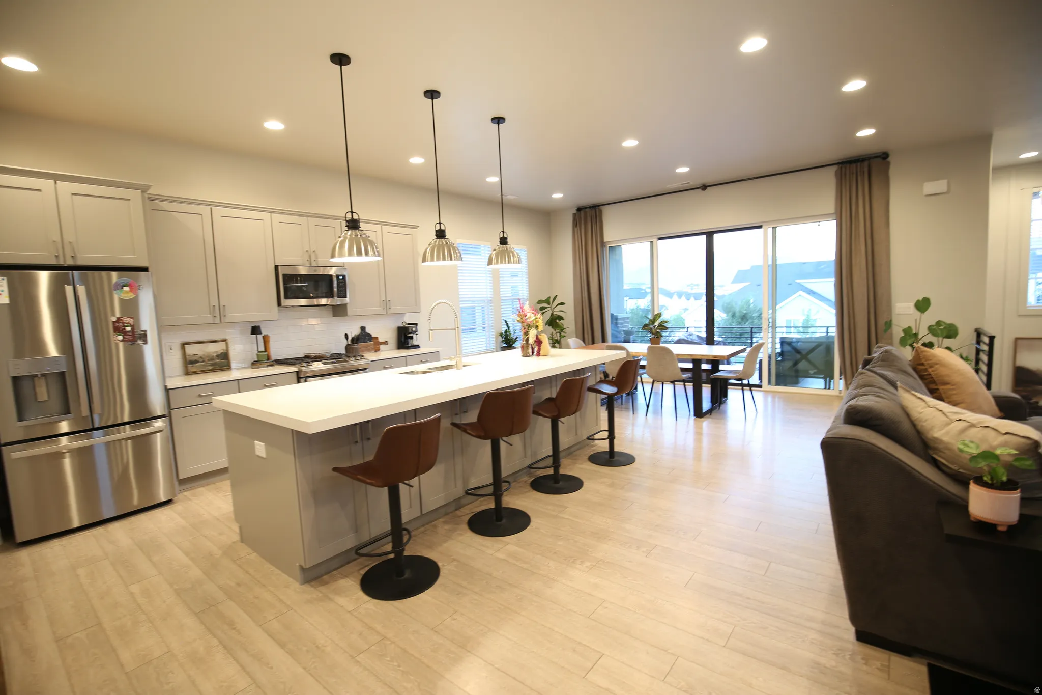 Kitchen featuring stainless steel appliances, a kitchen bar, open floor plan, gray cabinetry, and pendant lighting