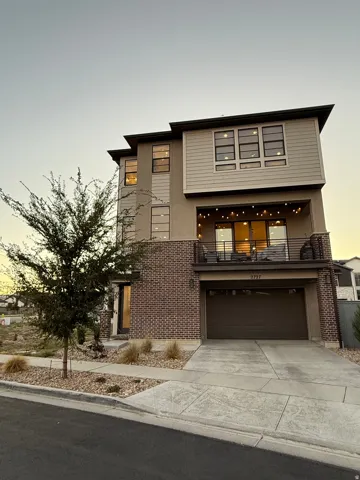 Contemporary house with concrete driveway, a balcony, brick siding, and a garage