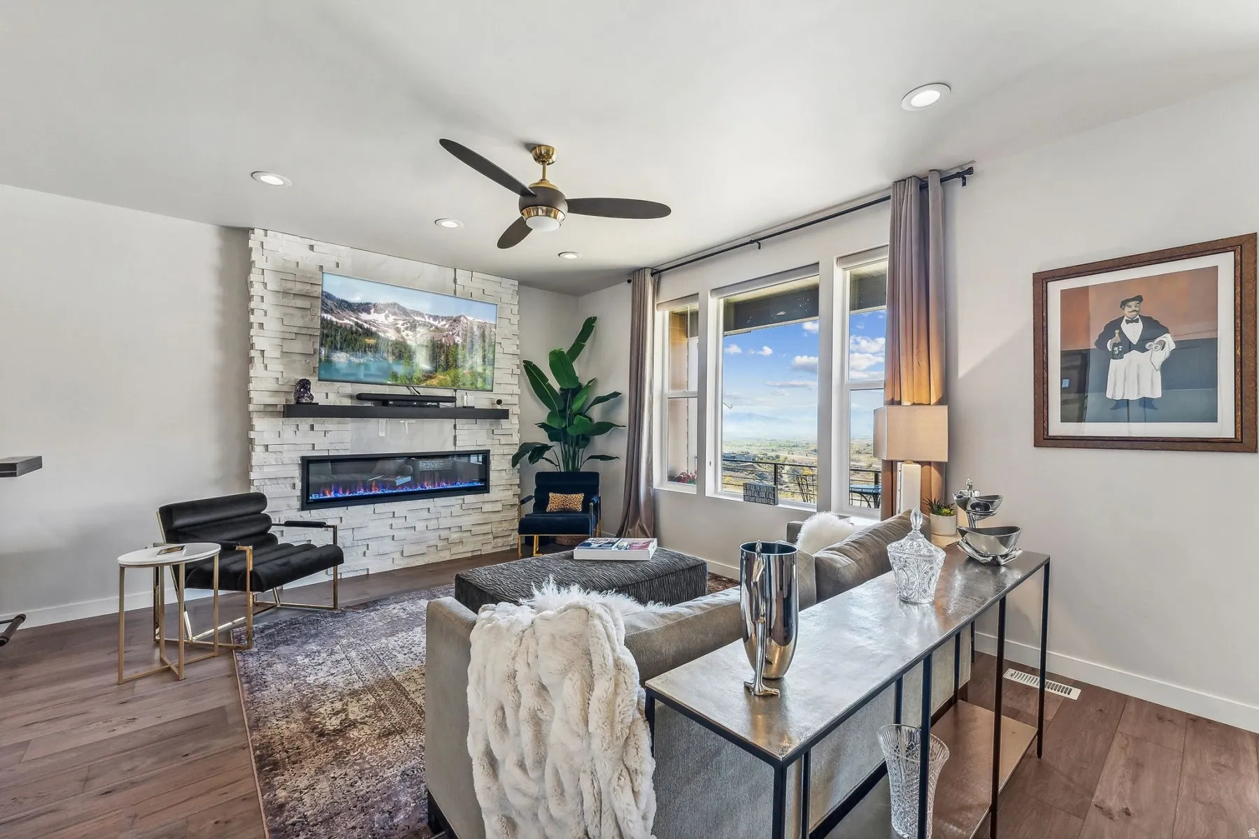 Living room with a fireplace, ceiling fan, and wood-type flooring