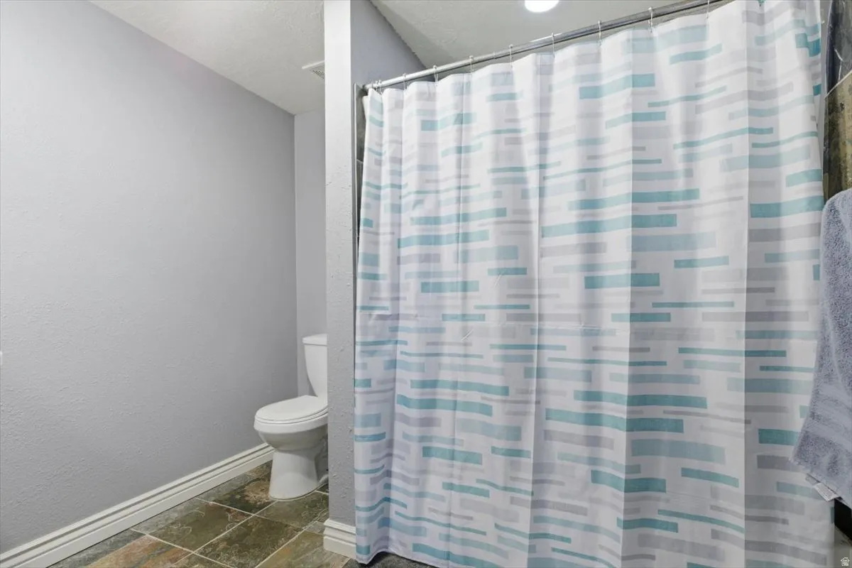 Bathroom featuring stone tile floors and a shower with curtain