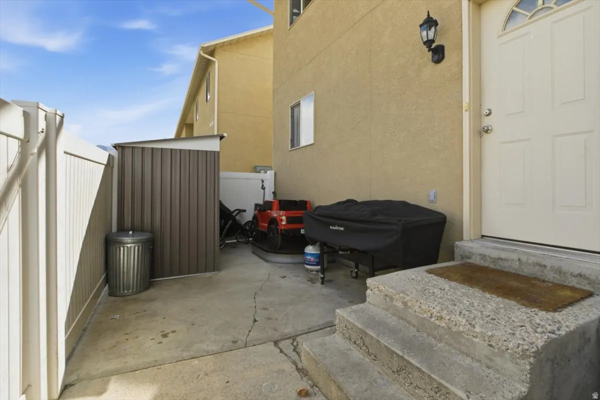 View of home's exterior with stucco siding, a patio area, and a storage unit