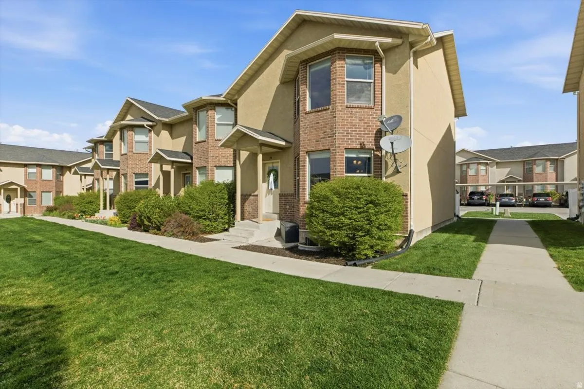 View of front of home featuring a front lawn, stucco siding, brick siding, and a residential view